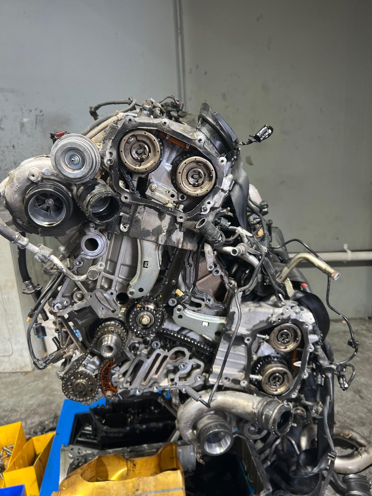 Twin-turbo V engine on a stand with its timing covers removed