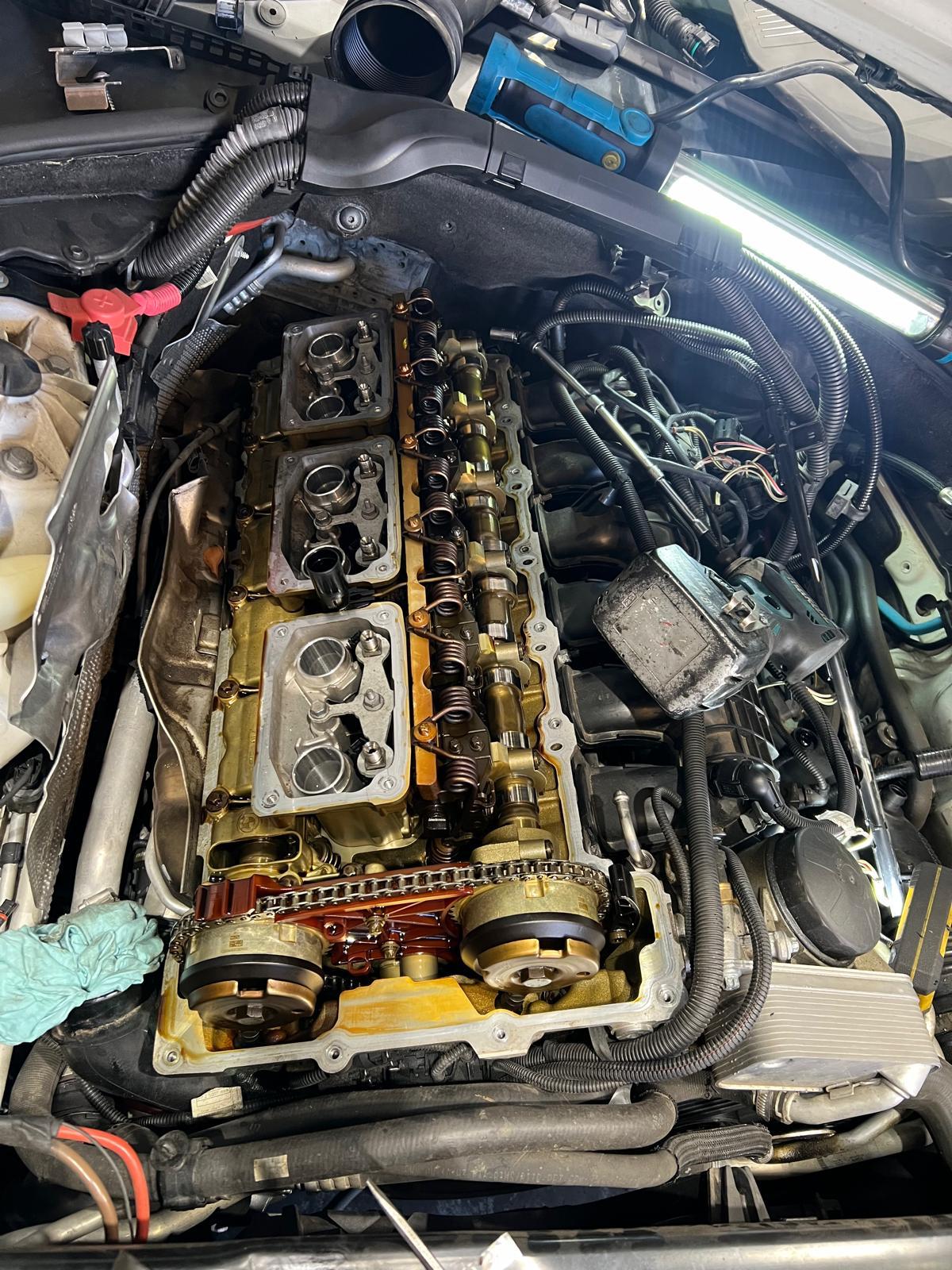 Cylinder head with the valve cover off, being serviced in the engine bay